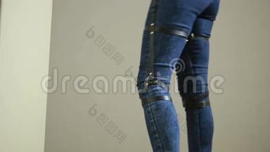 穿牛仔裤的女孩和皮革吊带新时尚潮流。 臀部的带子